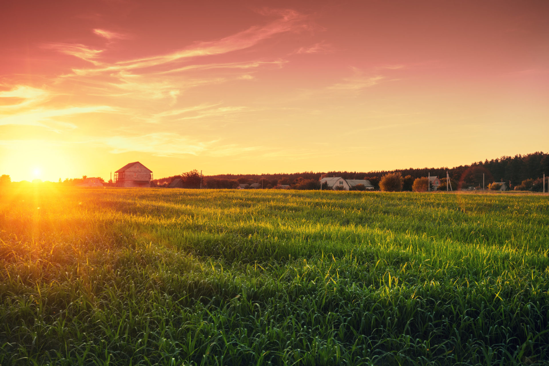 Rural landscape with beautiful gradient evening sky at sunset. Green field and village on horizon
